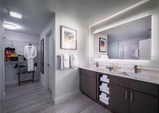 bathroom with vanity, hardwood / wood-style floors, a textured ceiling, and walk in shower