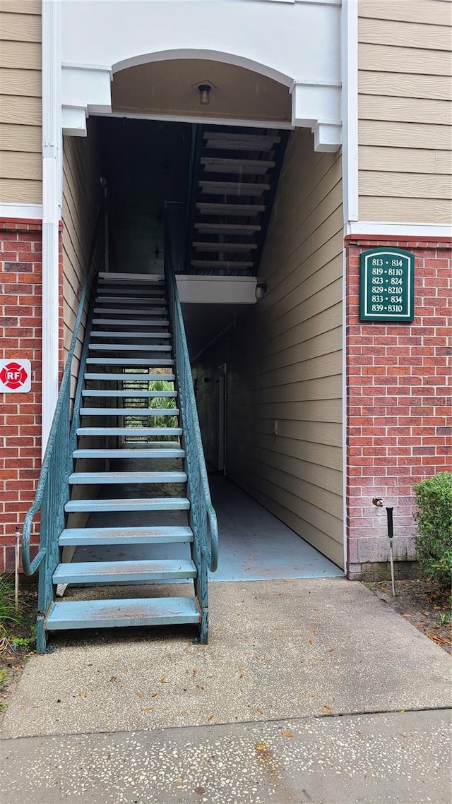 property entrance with an attached carport, concrete driveway, and brick siding