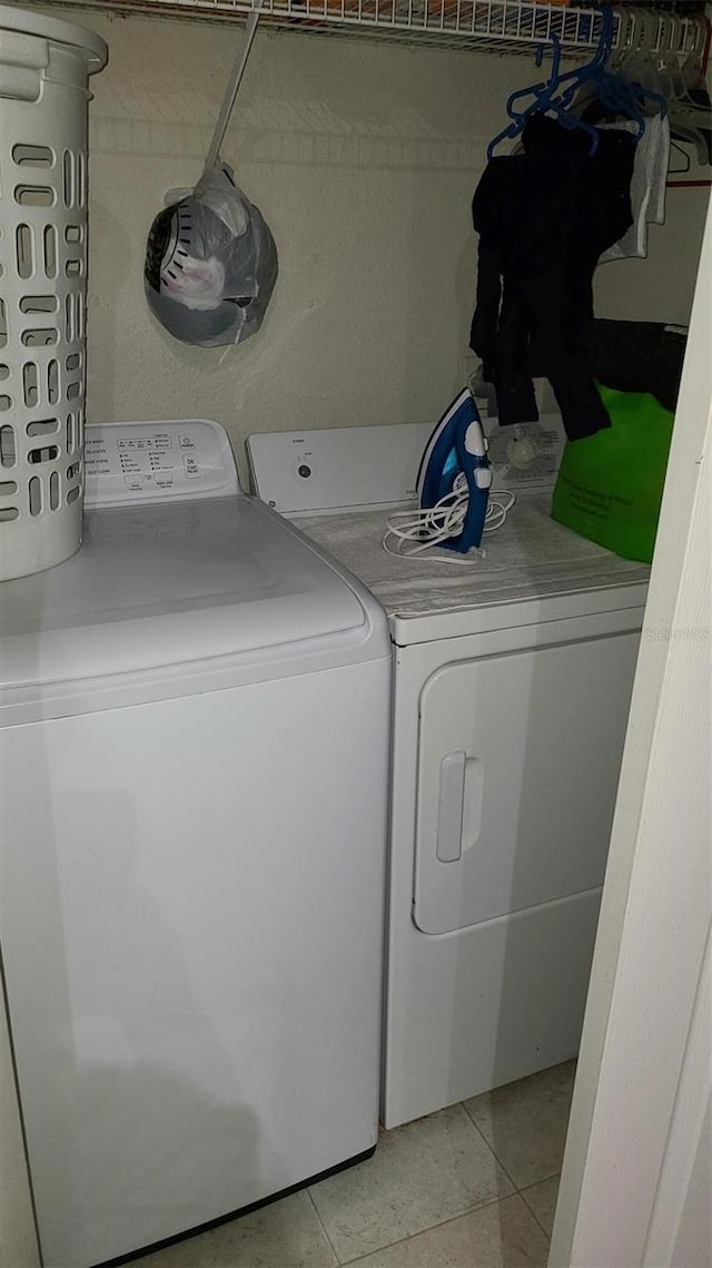 clothes washing area featuring laundry area, washing machine and dryer, and light tile patterned flooring