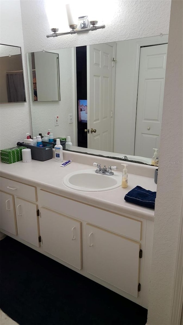 bathroom with a textured wall and vanity