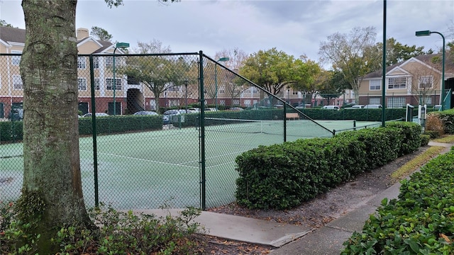 view of tennis court featuring a residential view and fence