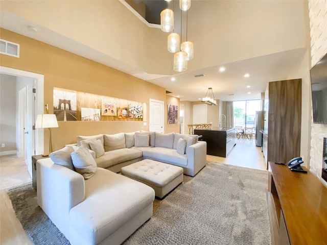 living room featuring sink, a towering ceiling, and an inviting chandelier