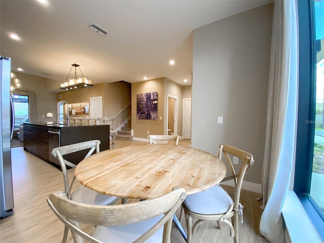 dining area with an inviting chandelier and light hardwood / wood-style flooring