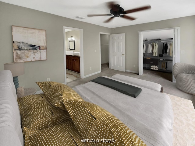 bedroom featuring a closet, ceiling fan, connected bathroom, a spacious closet, and light colored carpet