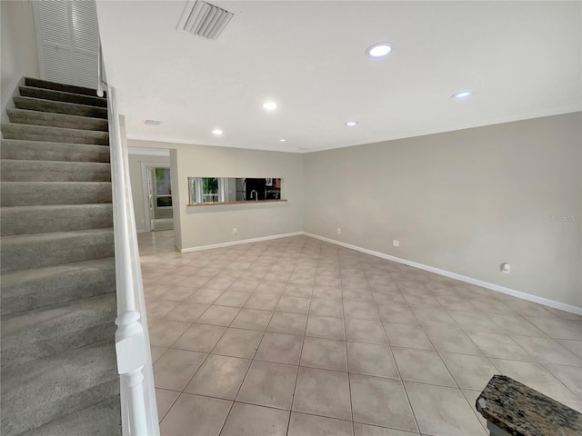 basement featuring light tile floors, black refrigerator, and ornamental molding