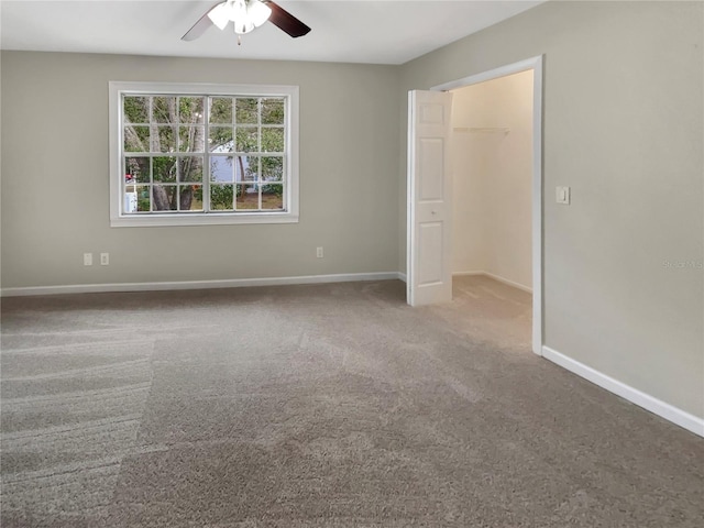 unfurnished bedroom with carpet floors, a spacious closet, a closet, and ceiling fan