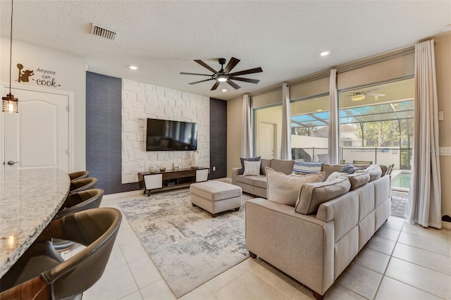 living room featuring light tile flooring, ceiling fan, and a textured ceiling