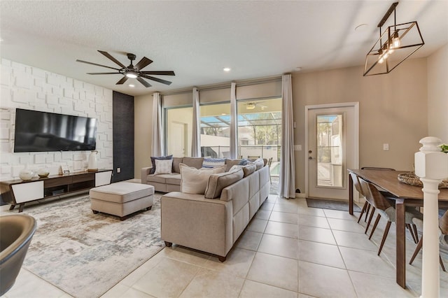 living room with light tile floors, a textured ceiling, and ceiling fan with notable chandelier