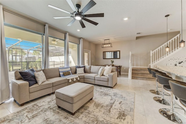 tiled living room featuring ceiling fan with notable chandelier