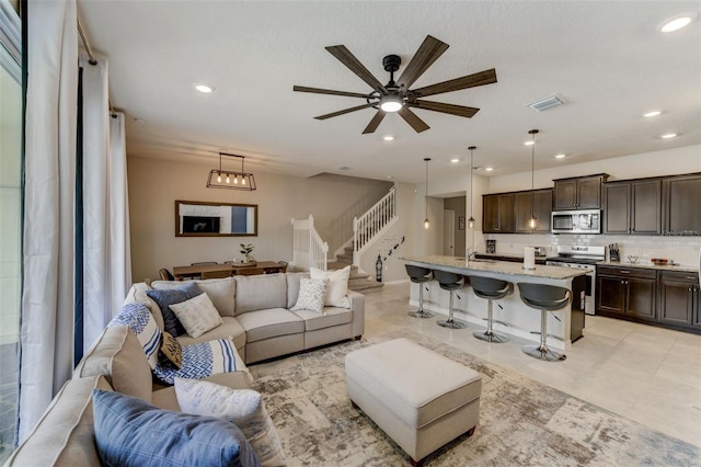 tiled living room with ceiling fan with notable chandelier and sink