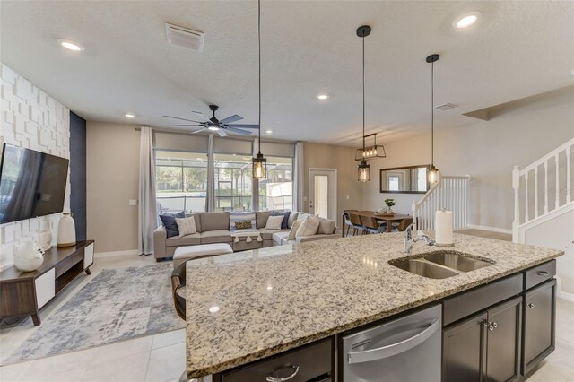 kitchen with ceiling fan, a center island with sink, hanging light fixtures, dishwasher, and sink