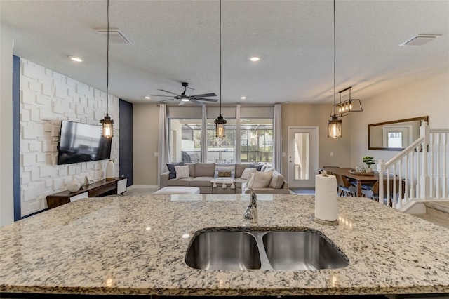 kitchen featuring a kitchen island with sink, ceiling fan, sink, and pendant lighting