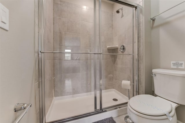 bathroom with toilet and a shower with door