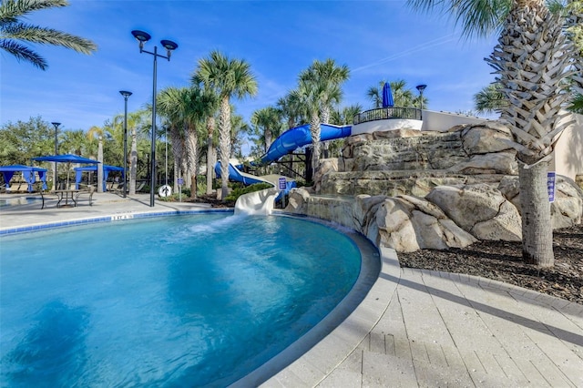 view of swimming pool with a water slide and a patio area