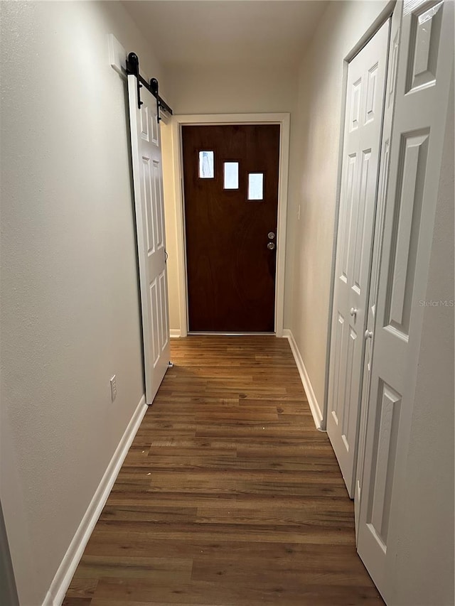 doorway to outside with a barn door and dark wood-type flooring