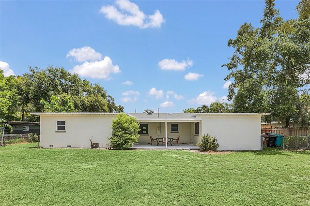 rear view of property featuring a patio area and a lawn