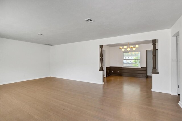 spare room featuring hardwood / wood-style floors and an inviting chandelier