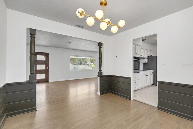 empty room featuring light hardwood / wood-style flooring and a notable chandelier