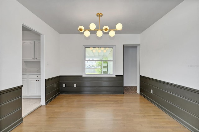 unfurnished room featuring light hardwood / wood-style flooring and an inviting chandelier