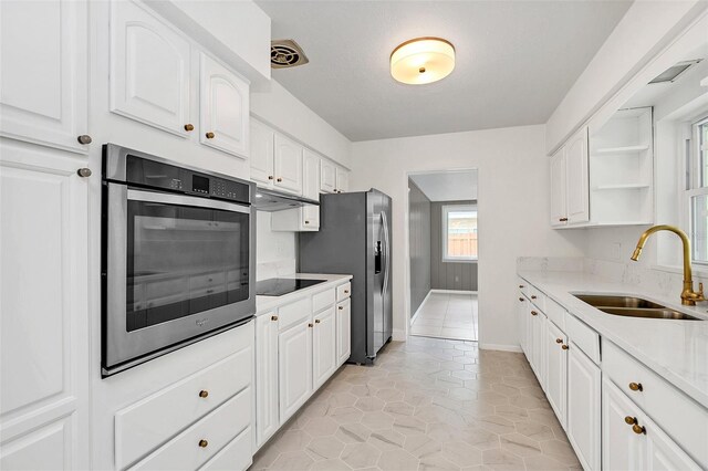 kitchen featuring sink, white cabinetry, light tile patterned floors, and stainless steel appliances