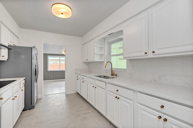 kitchen featuring sink, light stone countertops, light tile patterned flooring, and white cabinets