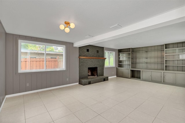 unfurnished living room with beamed ceiling, light tile patterned floors, brick wall, and a fireplace