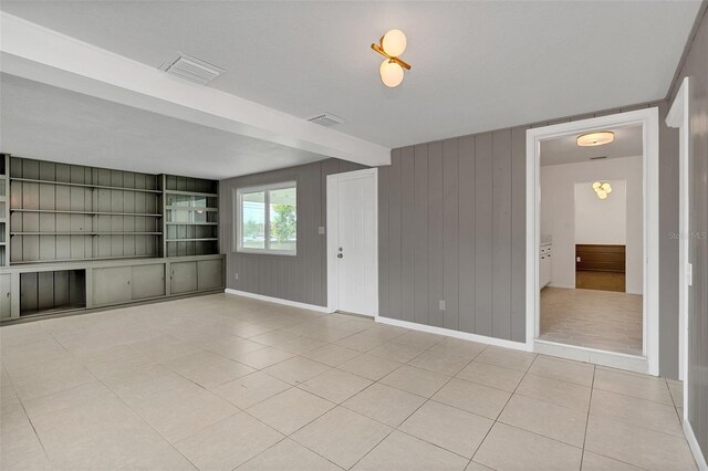 empty room featuring light tile patterned flooring and beam ceiling