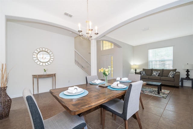 dining space featuring dark tile flooring and a chandelier