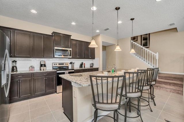 kitchen featuring light tile flooring, backsplash, hanging light fixtures, and stainless steel appliances