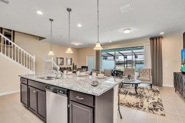 kitchen with light stone counters, a center island with sink, decorative light fixtures, and dishwasher