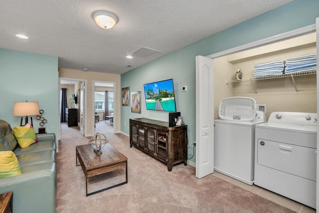 interior space featuring washer hookup, washer and clothes dryer, a textured ceiling, and light colored carpet