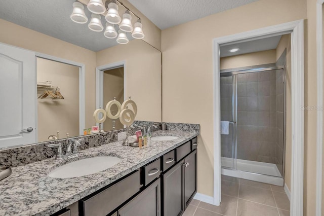 bathroom featuring walk in shower, vanity with extensive cabinet space, tile floors, dual sinks, and a textured ceiling