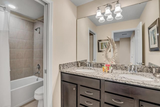 full bathroom with tiled shower / bath, toilet, a chandelier, and dual vanity