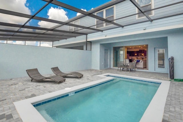 view of swimming pool featuring glass enclosure and a patio