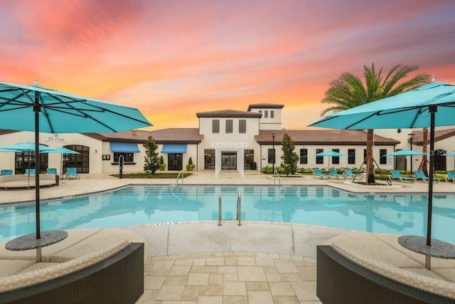 pool at dusk featuring french doors and a patio