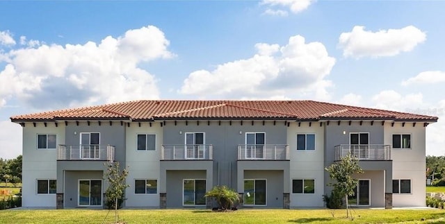 rear view of property featuring a balcony and a lawn