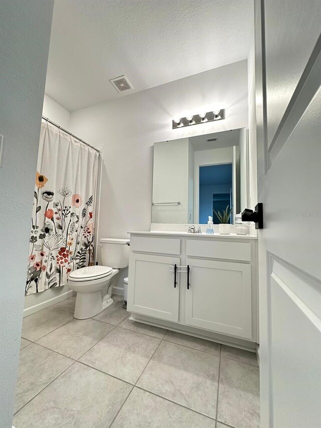 bathroom featuring toilet, a textured ceiling, vanity, and tile flooring