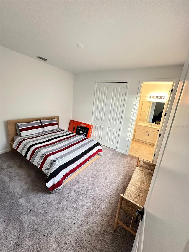 carpeted bedroom with ensuite bath and a closet