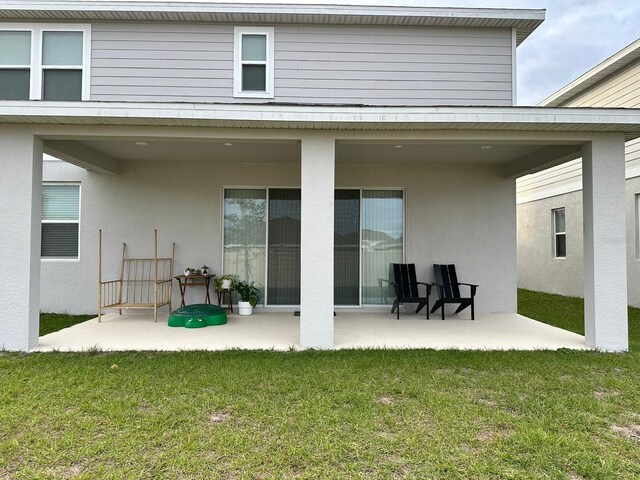 back of property featuring a lawn and a patio