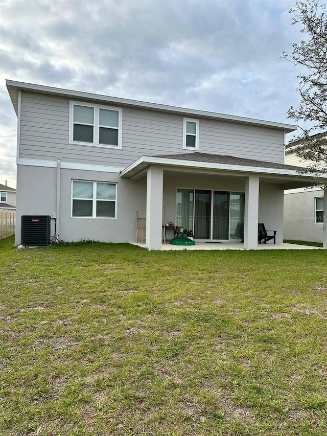 rear view of house with central AC, a lawn, and a patio area