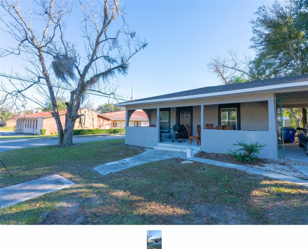 view of front facade featuring a front lawn, covered porch, and a carport