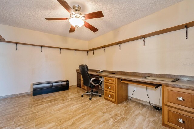 office area featuring a textured ceiling, ceiling fan, and built in desk