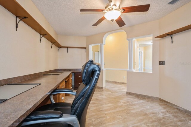 tiled office space featuring a textured ceiling, ceiling fan, and decorative columns