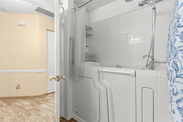 bathroom featuring tile floors, washer / clothes dryer, and a textured ceiling