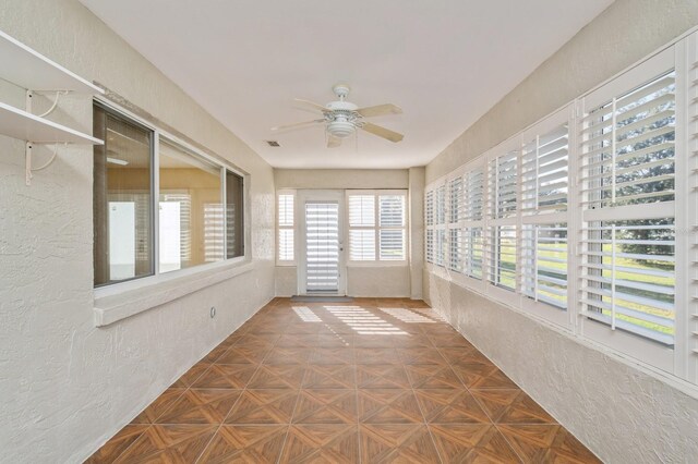 unfurnished sunroom with ceiling fan