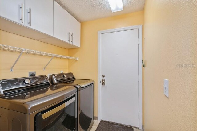 laundry room with a textured ceiling, washer and clothes dryer, cabinets, and electric dryer hookup