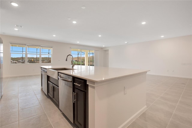 kitchen with light tile floors, a center island with sink, and dishwasher