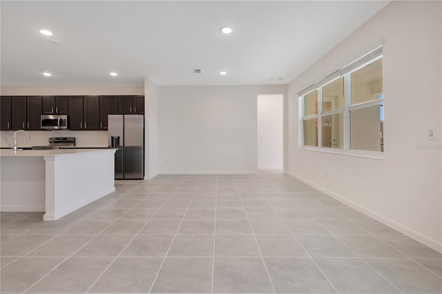 kitchen featuring dark brown cabinets, appliances with stainless steel finishes, light tile floors, and sink