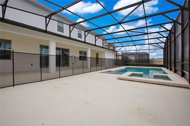 view of swimming pool featuring an in ground hot tub, glass enclosure, and a patio