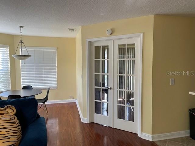 interior space with french doors, a textured ceiling, and dark wood-type flooring